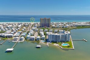 An aerial view of a coastal residential area with a large hotel, multiple buildings, and a marina. - Compass Point 610 | Dog Friendly | Waterfront | Pool | Docks | My Beach Getaways (Gulf Shores)