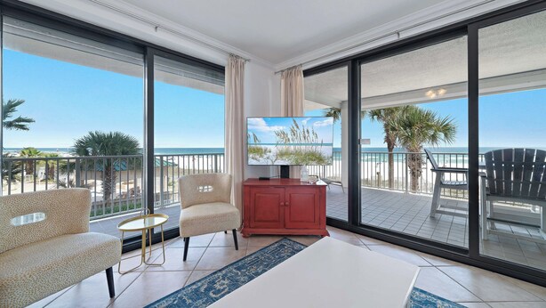 Ein Balkon mit Fernseher, Sitzgelegenheit und Blick auf den Strand.