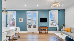 Un salon moderne avec un bar blanc, un canapé, une table basse et un téléviseur fixé au mur.