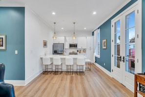 A modern kitchen with white cabinets, a central island with bar stools, stainless steel appliances, and pendant lighting.