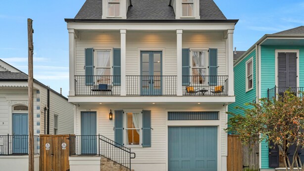 Une maison à deux étages avec un balcon, un garage et une clôture en bois.