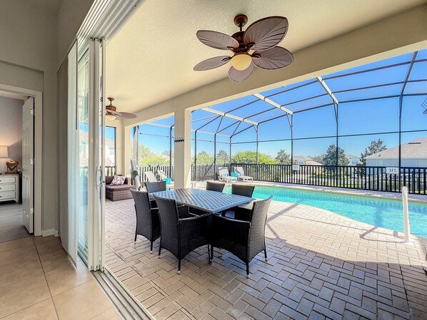 A covered patio with a pool, outdoor furniture, and a ceiling fan.