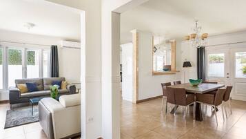 A modern living room with a sofa, coffee table, and a dining area with a table and chairs.