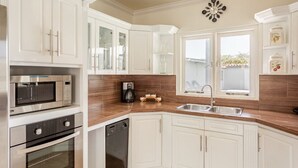 A modern kitchen with white cabinetry, stainless steel appliances, a wooden countertop, and a window providing natural light. - VILLA TOPAZ- 3BR/2BA-5 car min to Palm Beach (Noord)