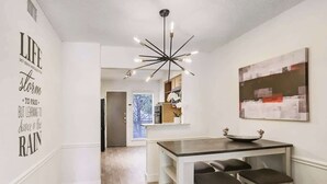 Una cocina moderna con una isla central, iluminación colgante y una pared con texto inspirador.