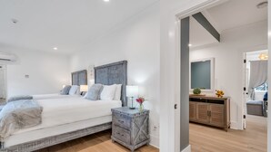 Een moderne slaapkamer met een groot bed, nachtkastjes, een kaptafel en een spiegel.