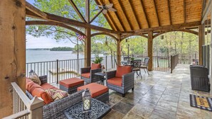 A covered outdoor seating area with wicker furniture, a ceiling fan, and a view of a lake. - Killen Time on Lake Martin (Dadeville)