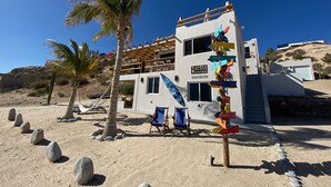 A modern beach house with a signpost indicating directions to various countries. - Beach Front Lofts 4 (el sargento)