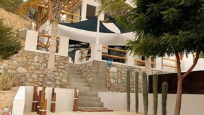 A modern building with a stone staircase, a wooden deck, and cacti. - Beach Front Lofts 4 (el sargento)