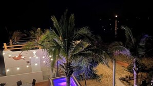 A rooftop bar with a pool, palm trees, and string lights. - Beach Front Lofts 4 (el sargento)
