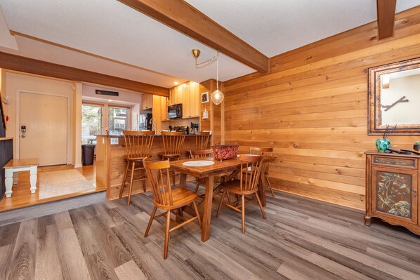 A wooden interior with a dining area, kitchen, and a mirror on the wall.