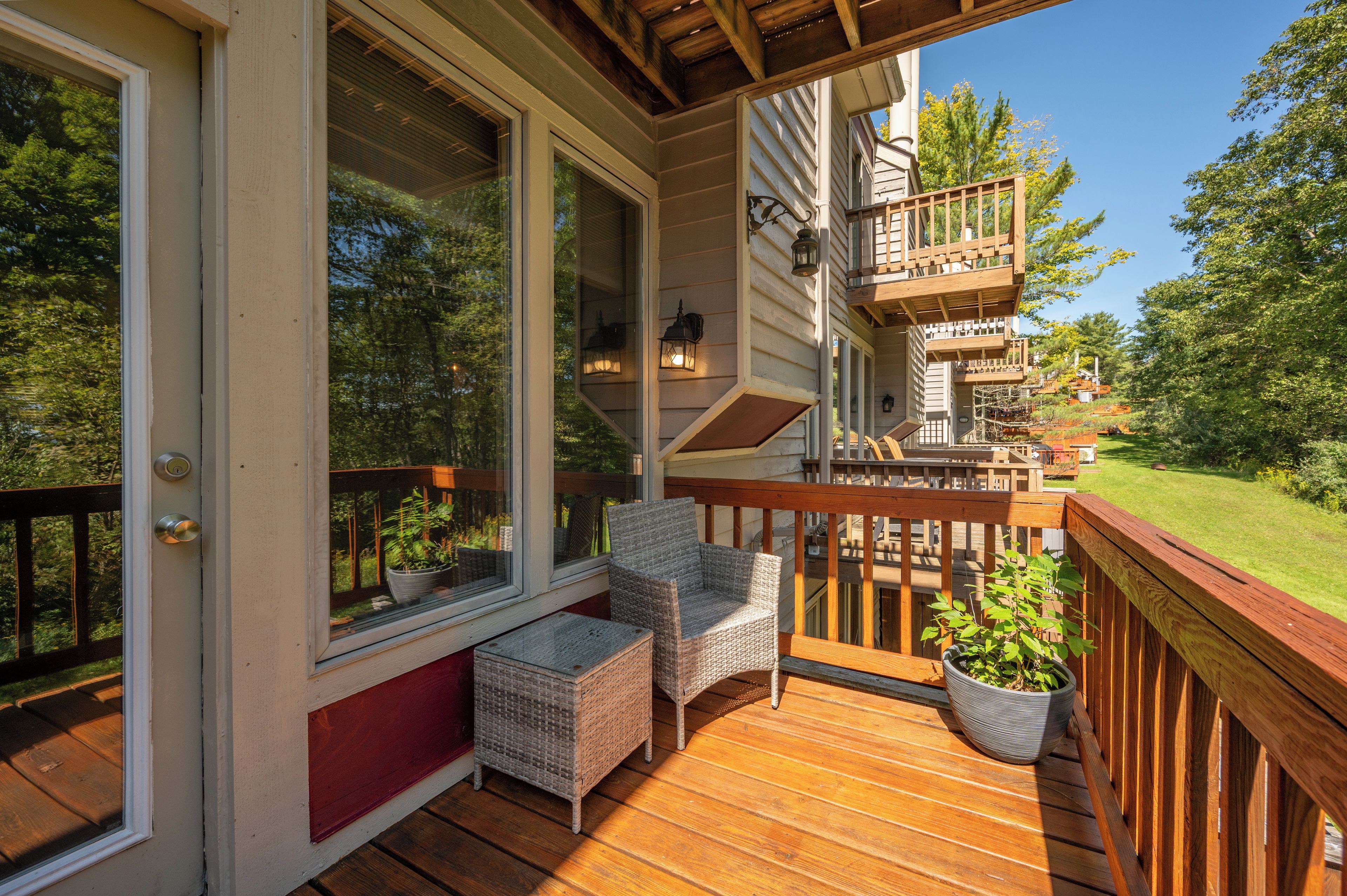 A wooden deck with wicker furniture and potted plants.