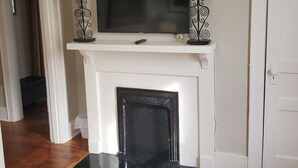 A white fireplace with a flat-screen TV mounted above it, flanked by two decorative candle holders. - Southern Charm: Home is minutes from downtown w/a cozy sitting porch (Nashville)