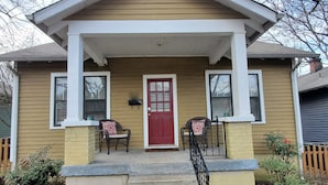A house with a front porch, a red door, two chairs, and a small garden. - Southern Charm: Home is minutes from downtown w/a cozy sitting porch (Nashville)