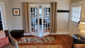 A living room with a sofa, a coffee table, a rug, and a door leading to a bedroom. - Southern Charm: Home is minutes from downtown w/a cozy sitting porch (Nashville)
