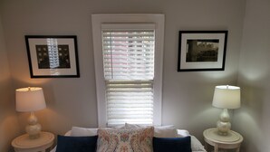 A neatly made bed with a patterned pillow, two bedside lamps, and framed pictures on the walls. - Southern Charm: Home is minutes from downtown w/a cozy sitting porch (Nashville)