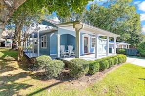 A two-story house with a covered porch and a small deck, surrounded by well-maintained hedges and trees. - Picturesque Home in Downtown Auburn (Auburn)