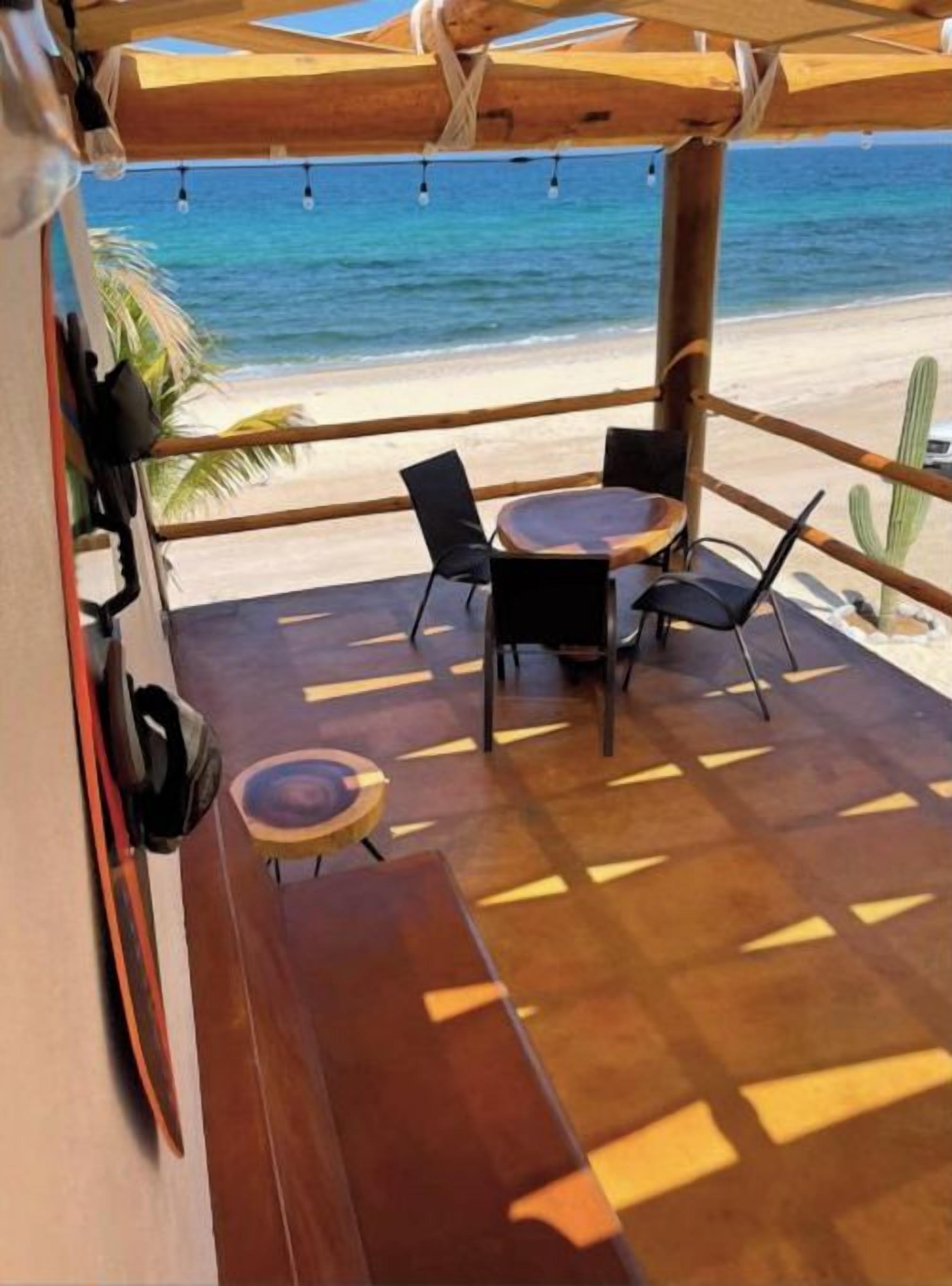 Een terras aan het strand met houten meubels en uitzicht op de oceaan.