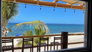 A beach view from a window with wooden railings and a palm tree. - Beach Front Lofts 2 (el sargento)