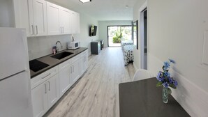 A modern kitchen with white cabinets, a built-in microwave, and a large window. - Satellite Motel - Seaclusion 104 (Treasure Island)