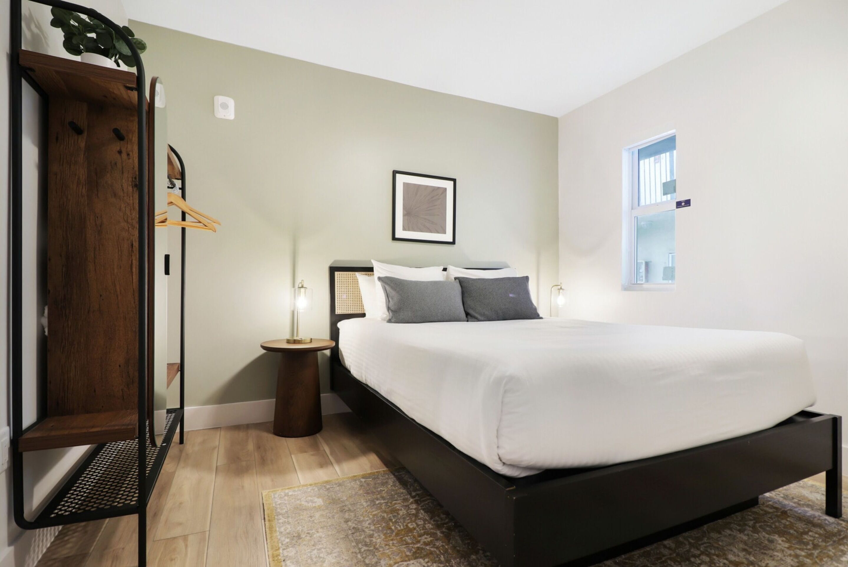 Quarto moderno com cama, mesas de cabeceira, planta pendente e janela.