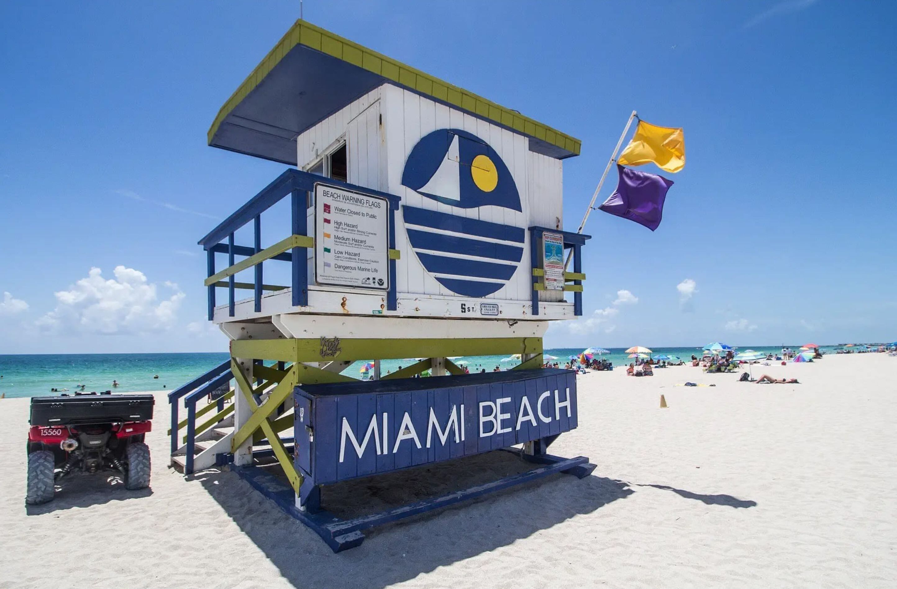 A lifeguard tower with a sign indicating beach warnings and the name "MIAMI BEACH".