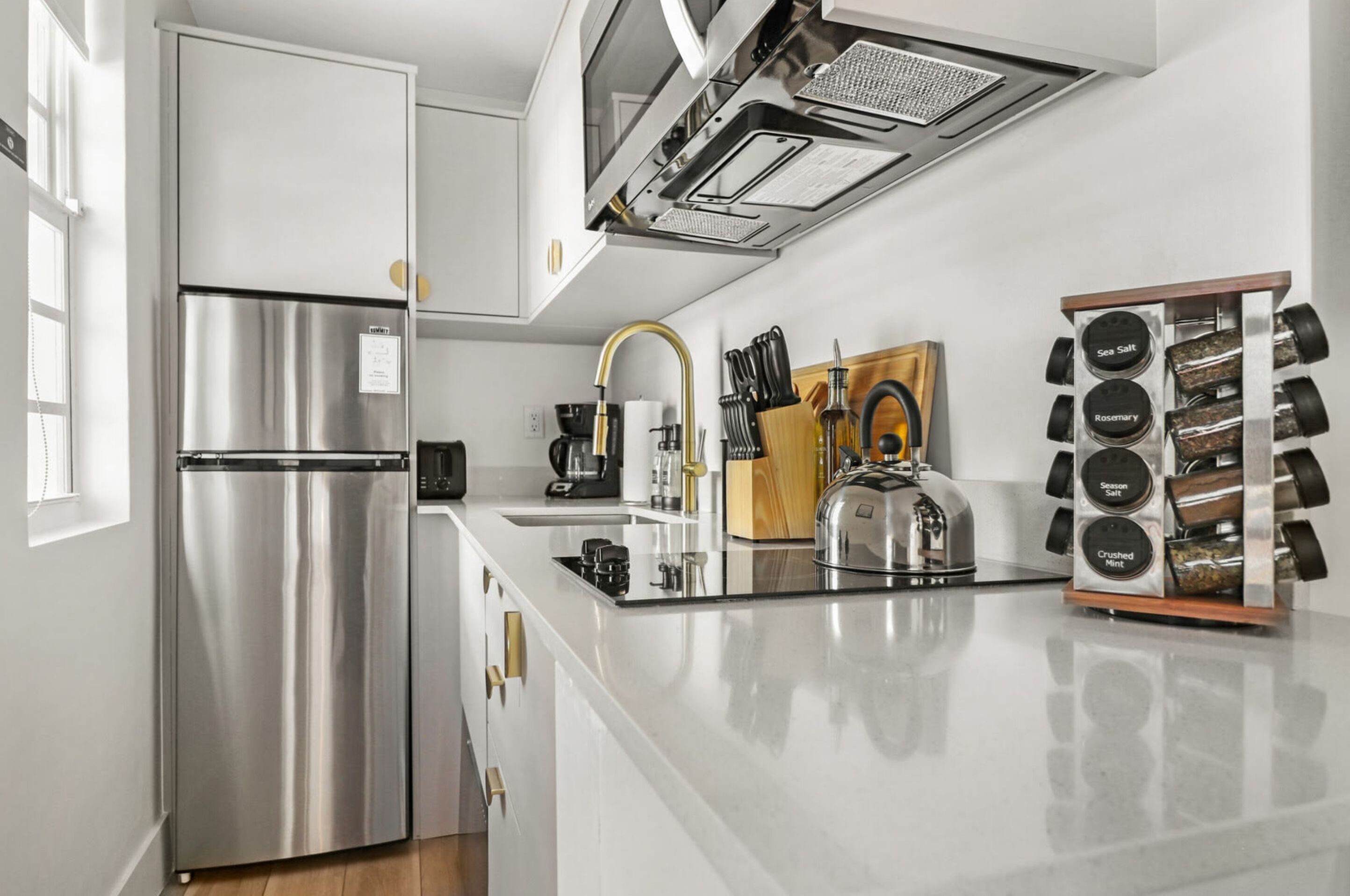 Una cucina moderna con un frigorifero in acciaio inossidabile, un piano cottura integrato e una macchina da caffè.
