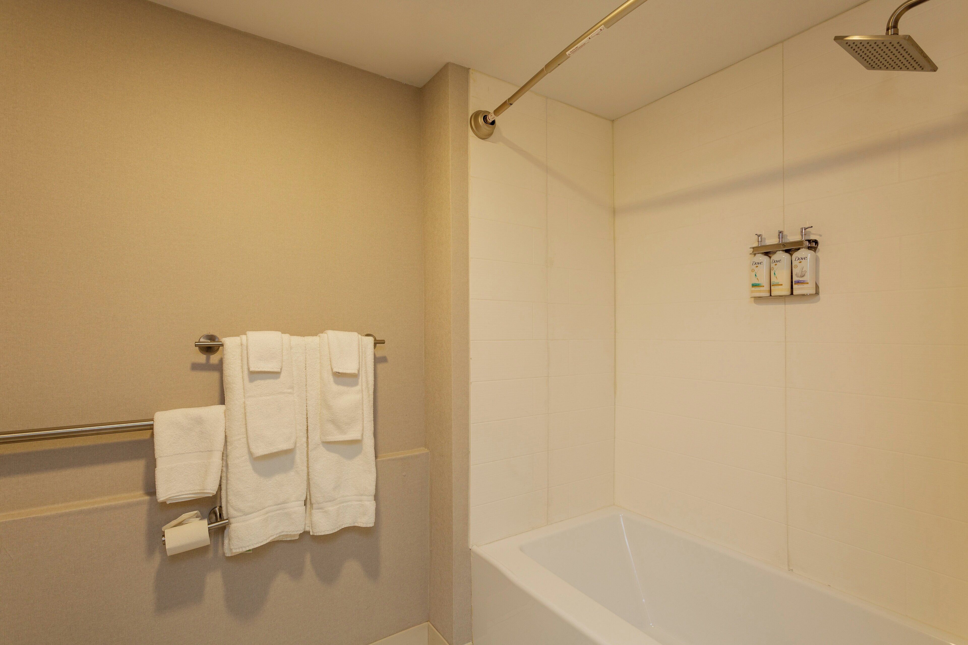 Ein Badezimmer mit einer Badewanne, einer Duschbrause und einem Handtuchhalter mit Handtüchern.