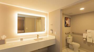 A modern bathroom with a large mirror, a sink, a toilet, and a shower area.