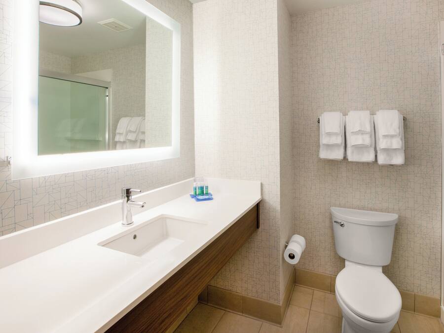 Un baño moderno con lavamanos, espejo y retrete blancos.