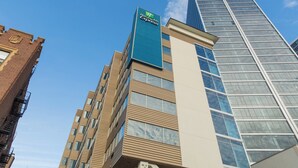 Un bâtiment de la chaîne Holiday Inn Express, doté d’un design moderne, avec une enseigne bleue bien visible et une façade combinant brique et verre.