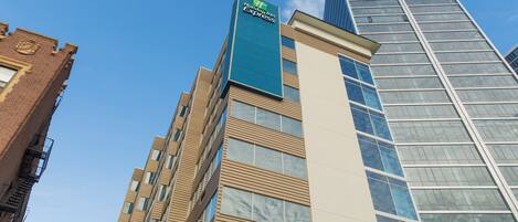 Edifício Holiday Inn Express com design moderno, destacando uma placa azul e uma combinação de fachadas de tijolo e vidro.