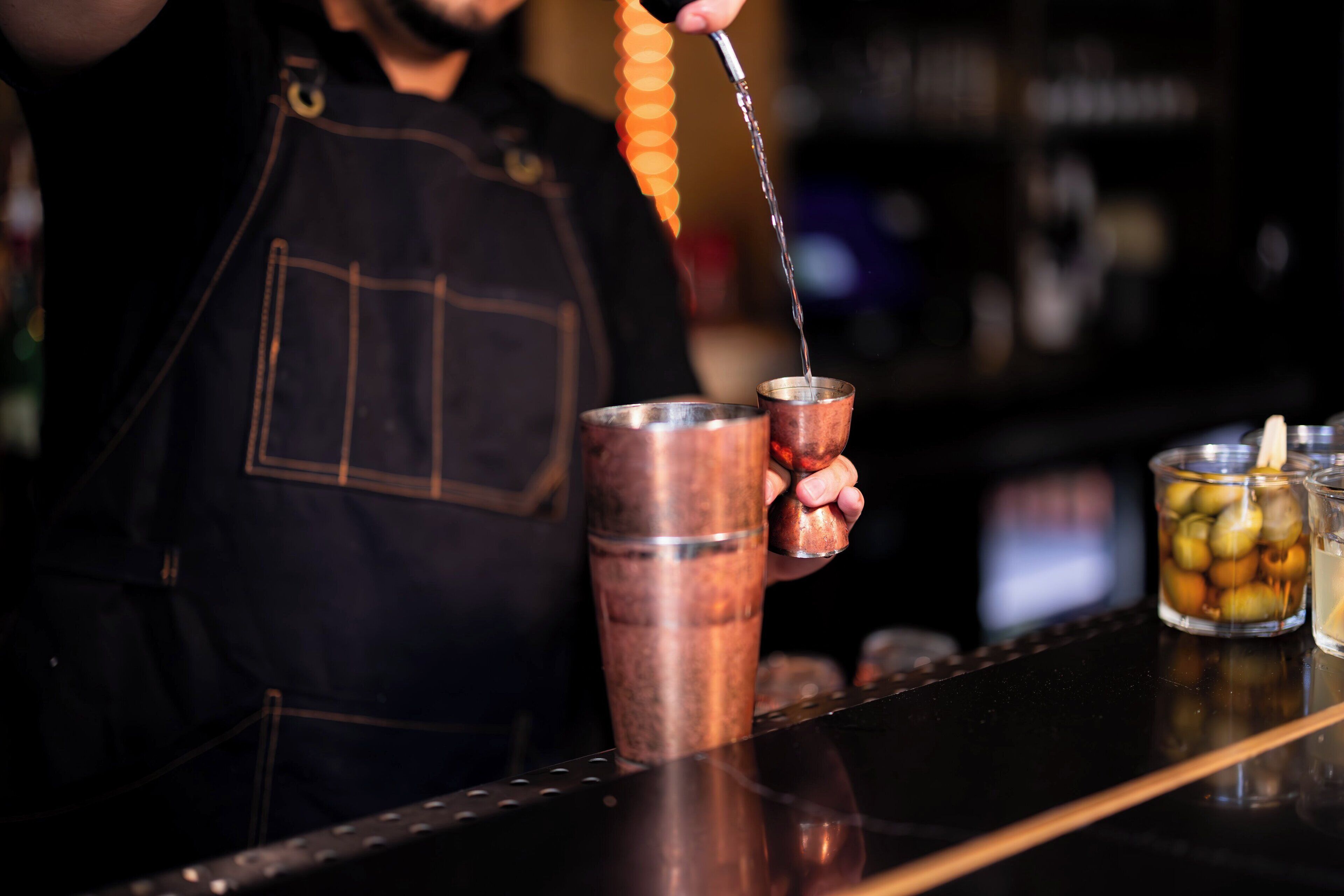 Ein Barkeeper gießt ein Getränk in einen Kupferbecher.