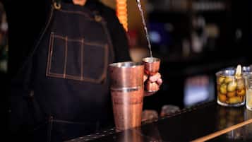 Ein Barkeeper gießt ein Getränk in einen Kupferbecher.