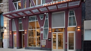 Entrada de un hotel de diseño moderno, con amplias ventanas y un cartel llamativo.
