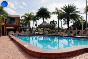 Una piscina con sillas de descanso y palmeras.
