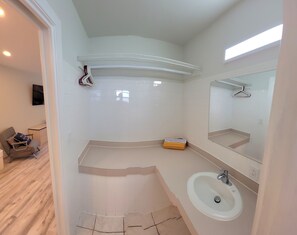 Un baño moderno con lavamanos blanco, espejo y paredes con azulejos.