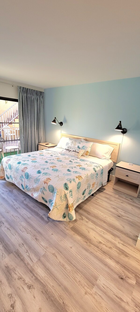 Un dormitorio con cama, dos lámparas de noche, una mesita de noche y vistas a un balcón.