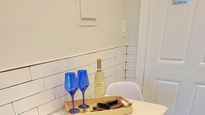 Una cocina con salpicadero de azulejos blancos, encimera con motas y una puerta blanca con un cartel de 'No Smoking'.