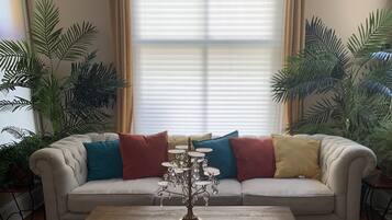 A living room with a beige sofa, a wooden coffee table, and a decorative metal stand.