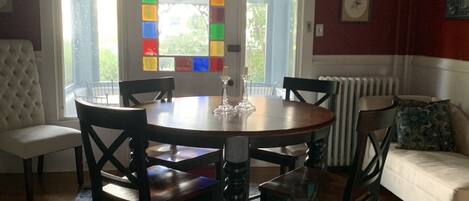 Un coin repas comprenant une table ronde, six chaises, un canapé blanc et un tapis à motifs.