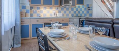 A compact kitchen with blue cabinets, a microwave, and a dishwasher.