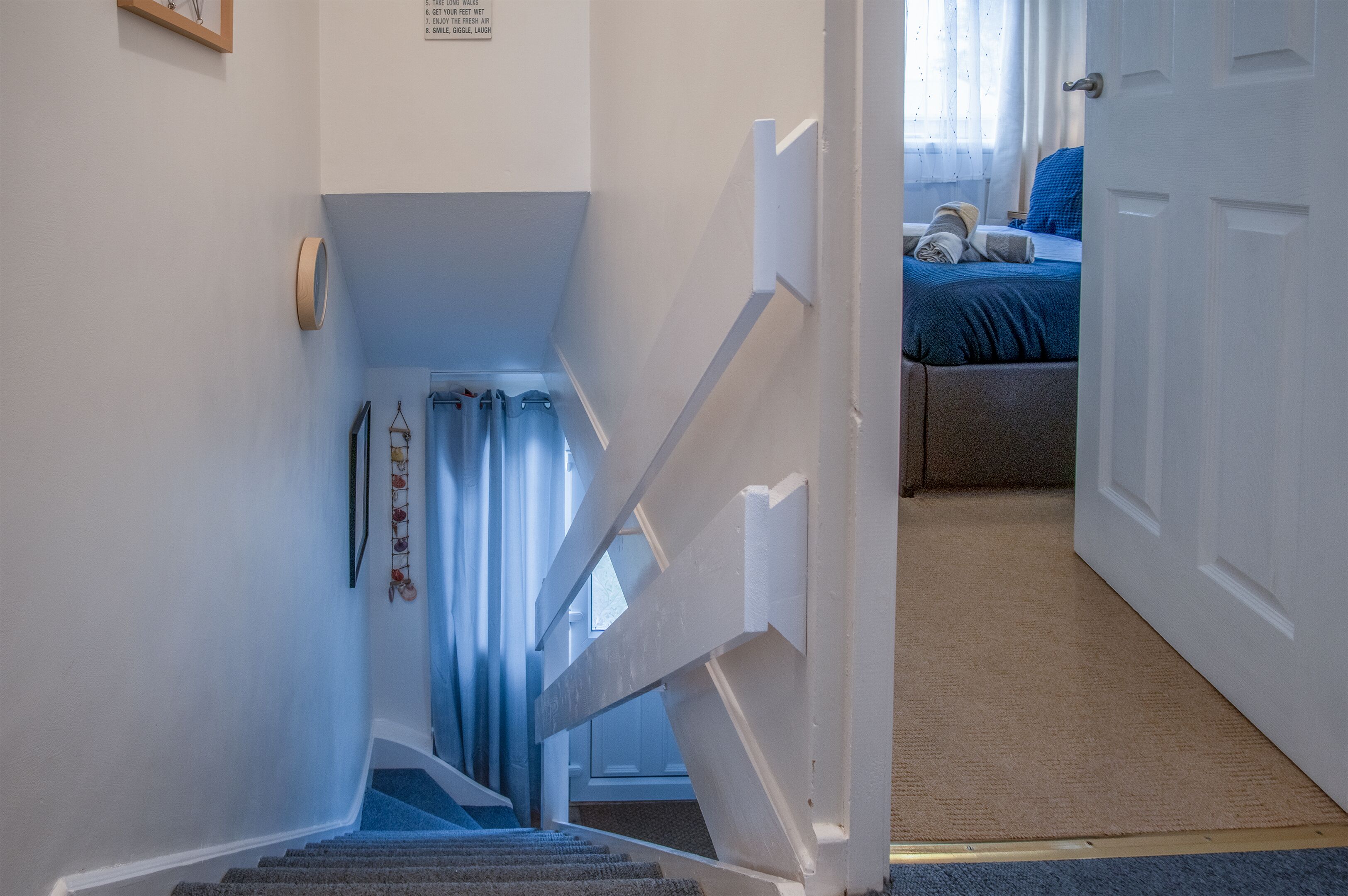 A staircase leading to a bedroom with a bed, a window, and a door.