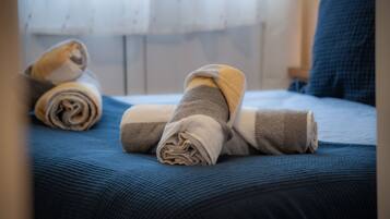 A bed with rolled towels and a blue blanket.