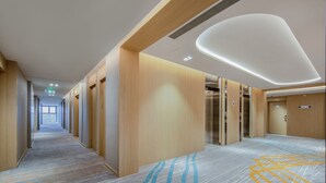 A hotel corridor with wooden paneling, a carpeted floor, and an elevator. - Holiday Inn Express Chengdu Tianfu Airport Zone by IHG (Chengdu)