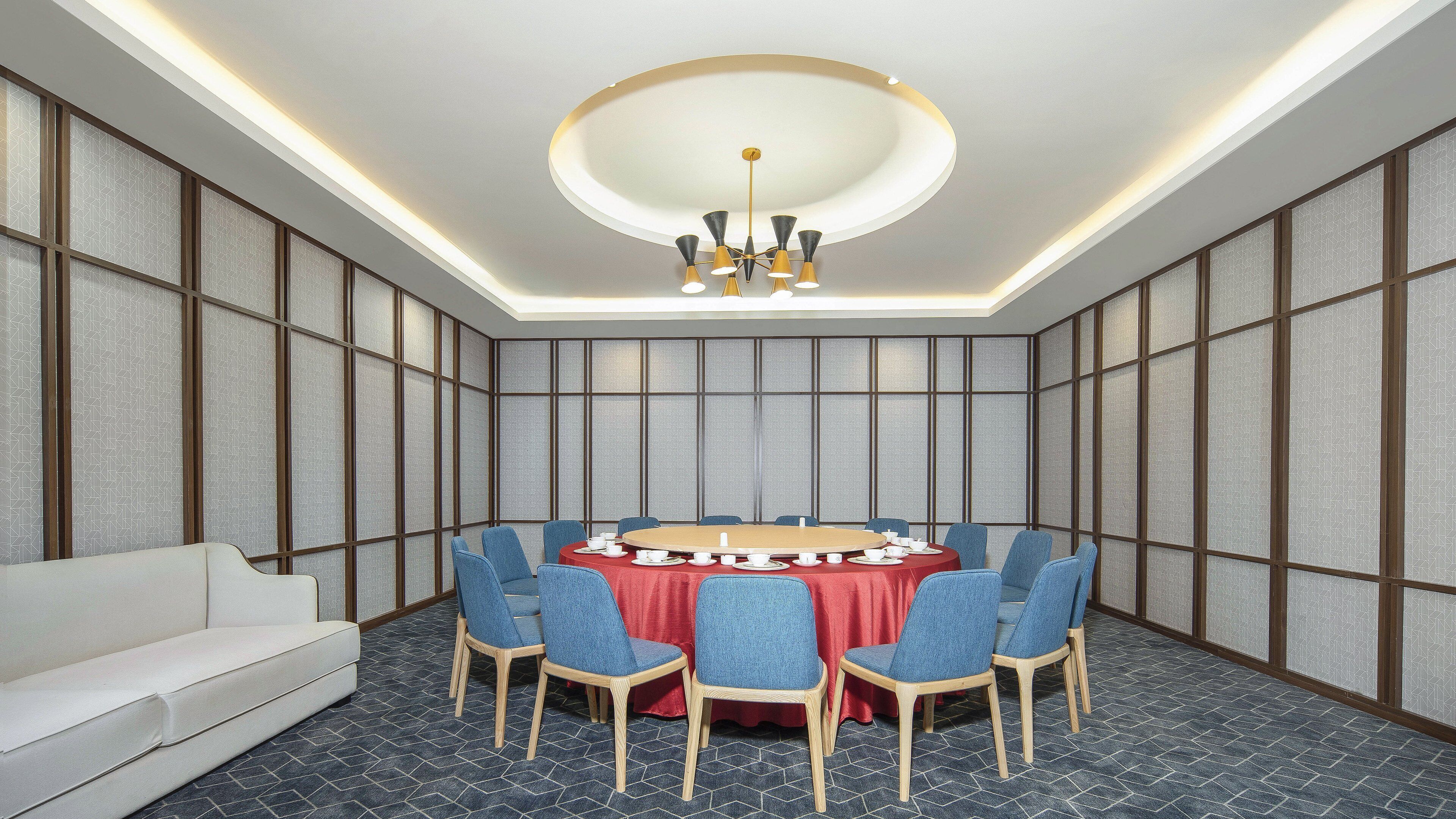 A conference room with a round table, blue chairs, and a white sofa.