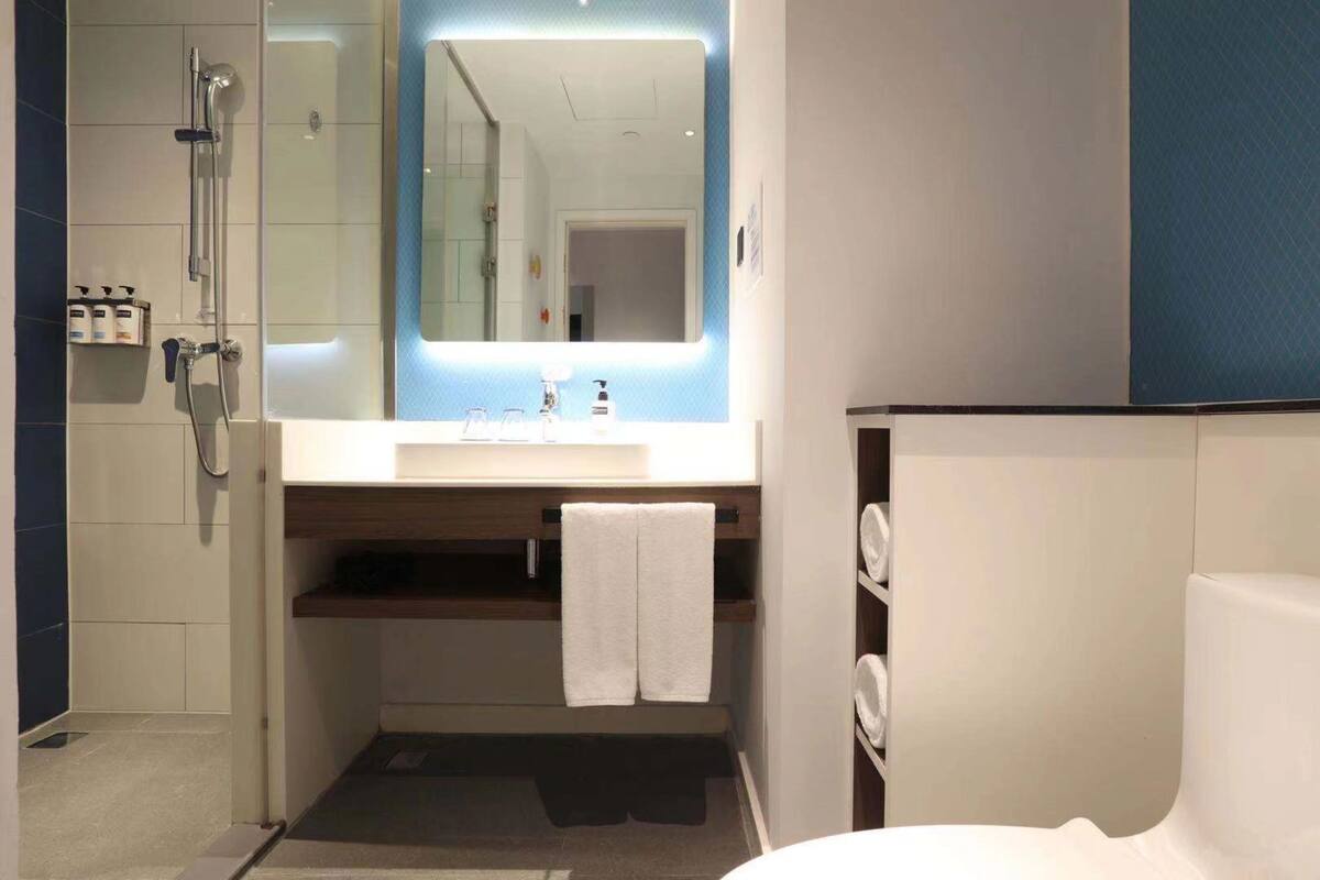 A modern bathroom with a shower, a sink with a mirror, and a towel rack.
