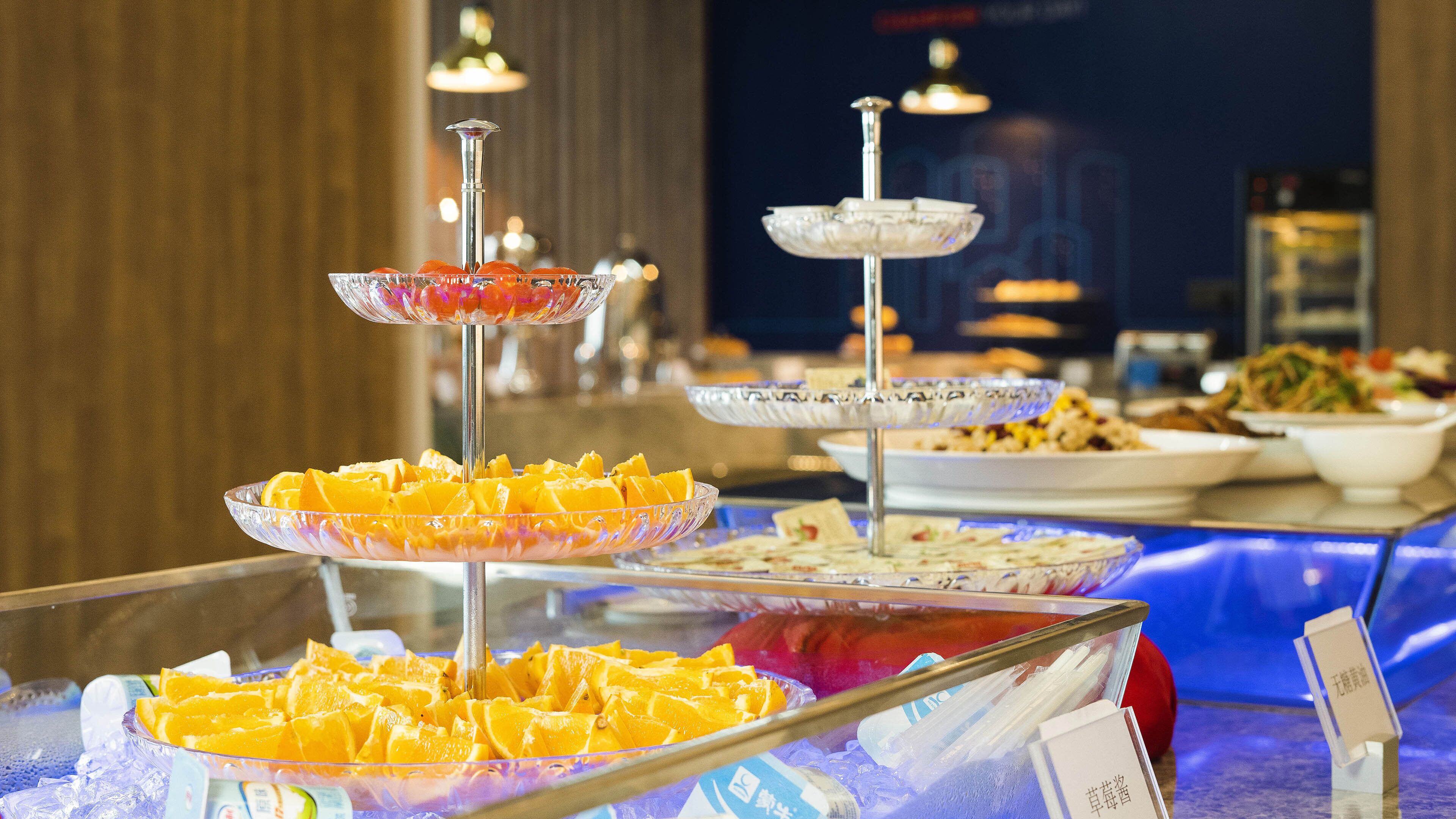 A buffet with various food items, including fruits and dishes, arranged on multiple serving stands.