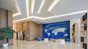 A modern lobby with a large world map mural, wooden paneling, and a mix of seating areas. - Holiday Inn Express Chengdu Tianfu Airport Zone by IHG (Chengdu)