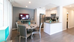 A modern kitchen with white cabinets, a stainless steel refrigerator, and a built-in oven.